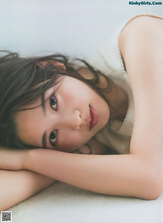 A woman laying on the floor with her head resting on her hands.