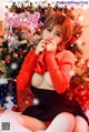 A woman in a red sweater sitting in front of a Christmas tree.