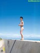 A woman in a bikini standing on a concrete wall.