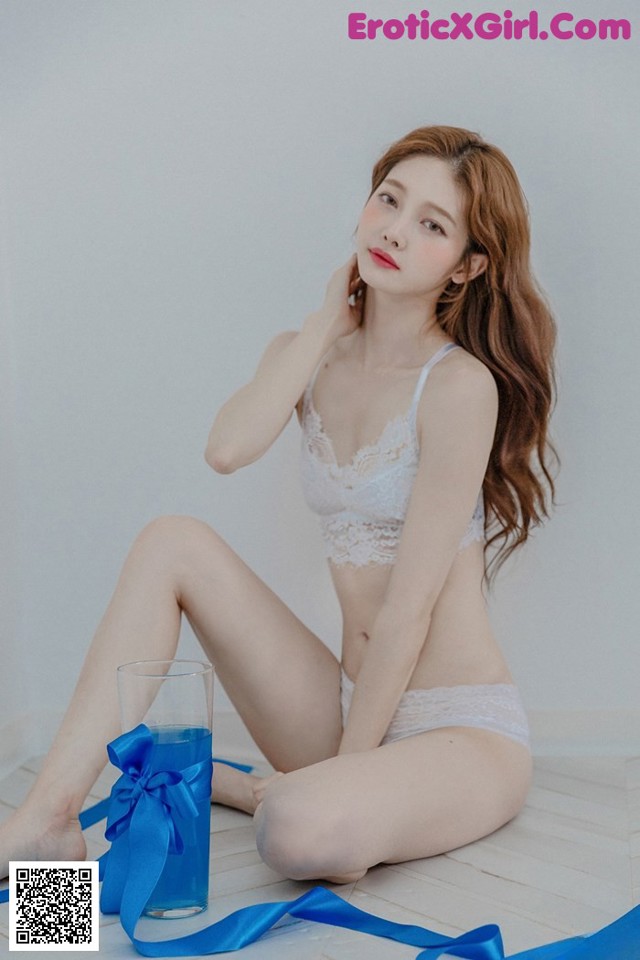 A woman sitting on the floor next to a glass of water.