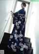 A woman in a blue kimono standing on a set of stairs.