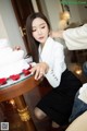 a woman sitting at a table with a cake in front of her