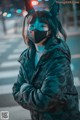 A woman wearing a cat ears mask standing on a city street.