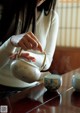 A woman pouring tea into a teapot on a table.