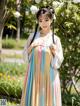 A woman in a colorful dress standing in a park.