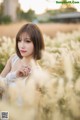 A woman in a white dress standing in a field of tall grass.