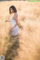 A woman in a white dress standing in a field.