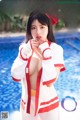 A woman in a red and white uniform posing by a pool.