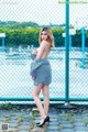 A woman standing in front of a chain link fence.